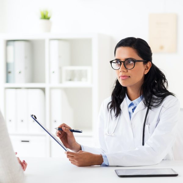 doctor with clipboard and woman at hospital